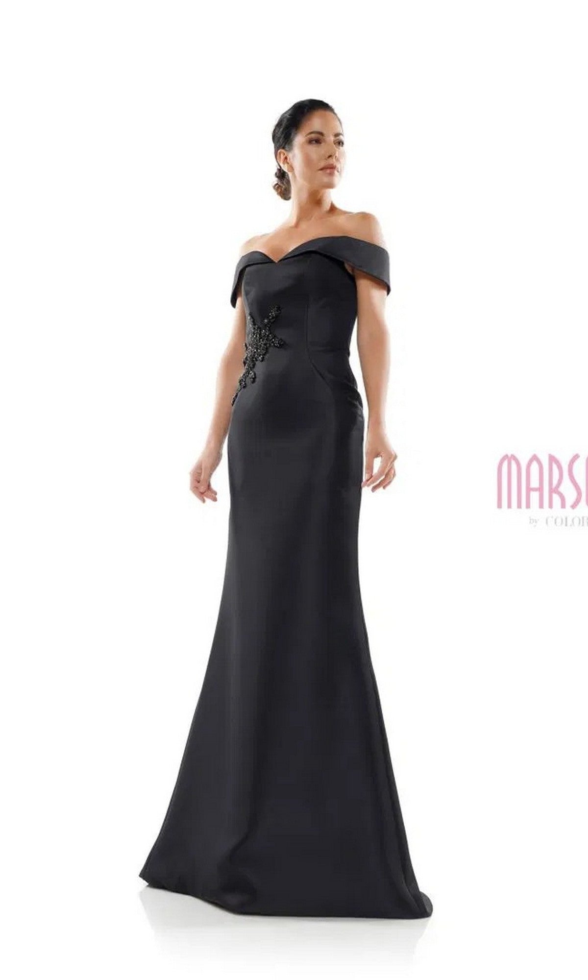 A woman models the Marsoni MV1003 long formal dress in black—an off-the-shoulder satin gown with beaded floral bodice—standing elegantly against a plain white background.